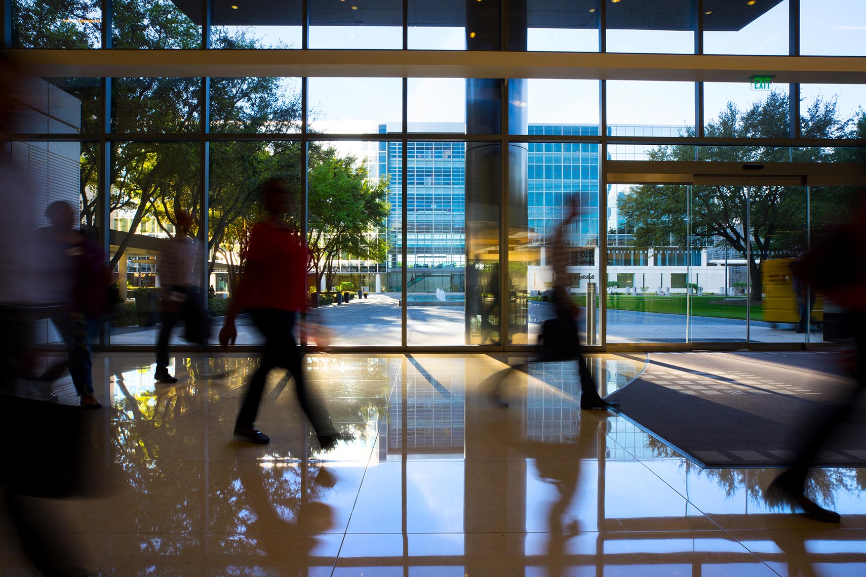 Business men and women walk in the lobby of a modern office building by a corporate  photographer in Houston