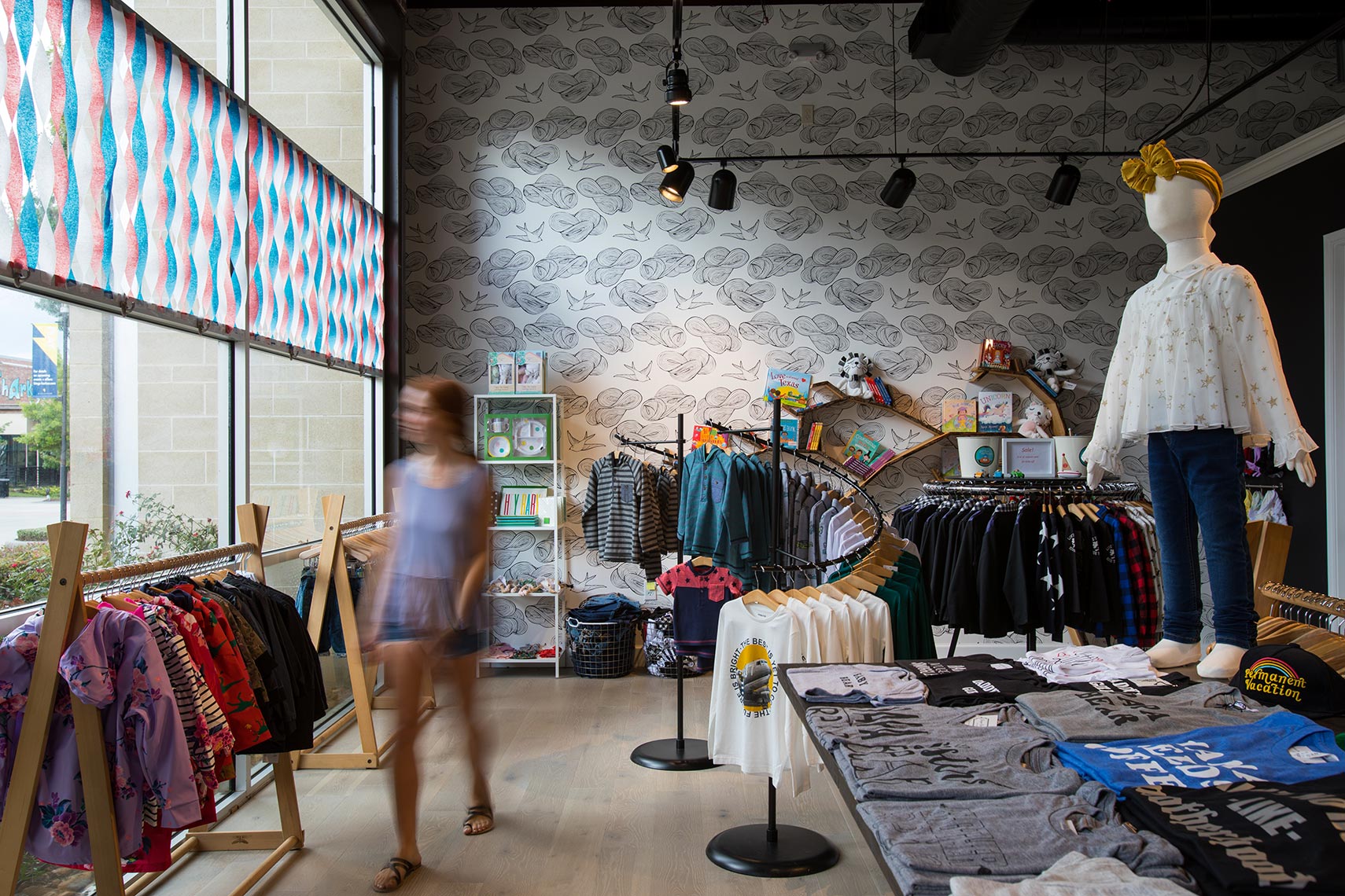 a shopper walks through a kids clothing store. an example of Retail interior design photography in Austin, Texas