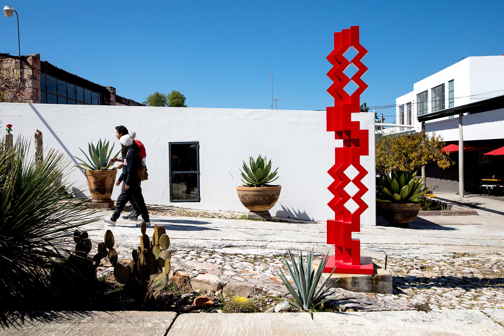 Visitors walk past a red sculpture at Fabrica La Aurora art gallery in San Miguel de Allende
